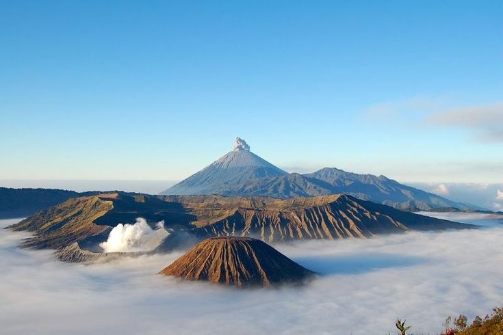 Kawah aktif Gunung Bromo mengeluarkan asap putih di tengah lautan pasir