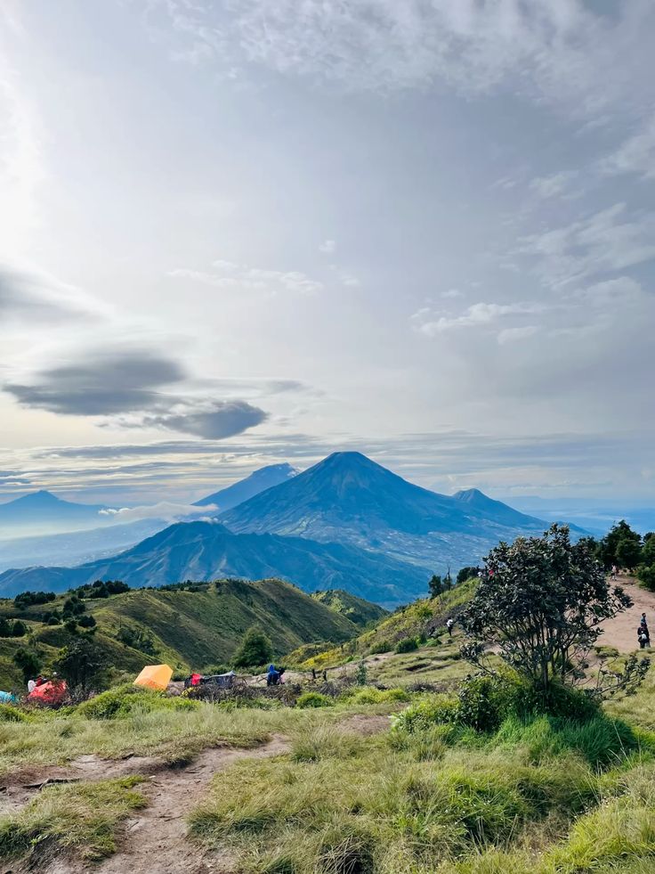 Tenda camping berjejer di puncak Gunung Prau dengan latar gunung Sindoro