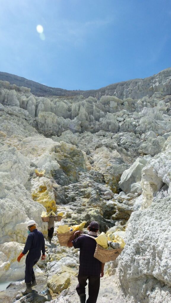 Starry sky above Mount Ijen with glowing blue fire in crater below