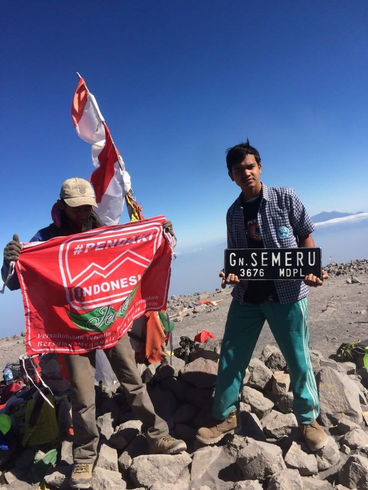 Pendaki sobat hikingdi padang rumput Kalimati dengan latar Gunung Semeru menjulang tinggi