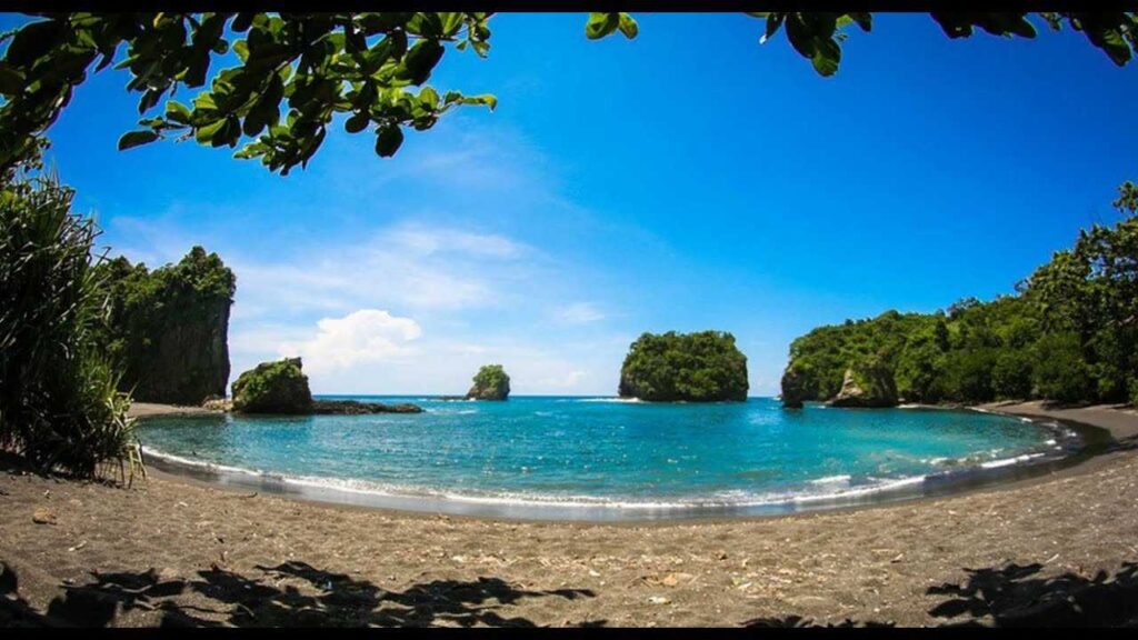 Hamparan pasir putih keabuan di Pantai Wedi Awu Malang dengan tebing hijau di kiri kanan membentuk panorama tapal kuda yang unik