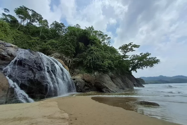 Air terjun setinggi 7 meter langsung jatuh ke pasir putih Pantai Banyu Anjlok Malang dengan latar Samudra Hindia