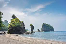 Pemandangan Pantai Licin yang alami dengan tebing karang dan air laut hijau tosca