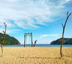 Pantai Sipelot dengan pasir putih kecokelatan dan formasi batu karang artistik